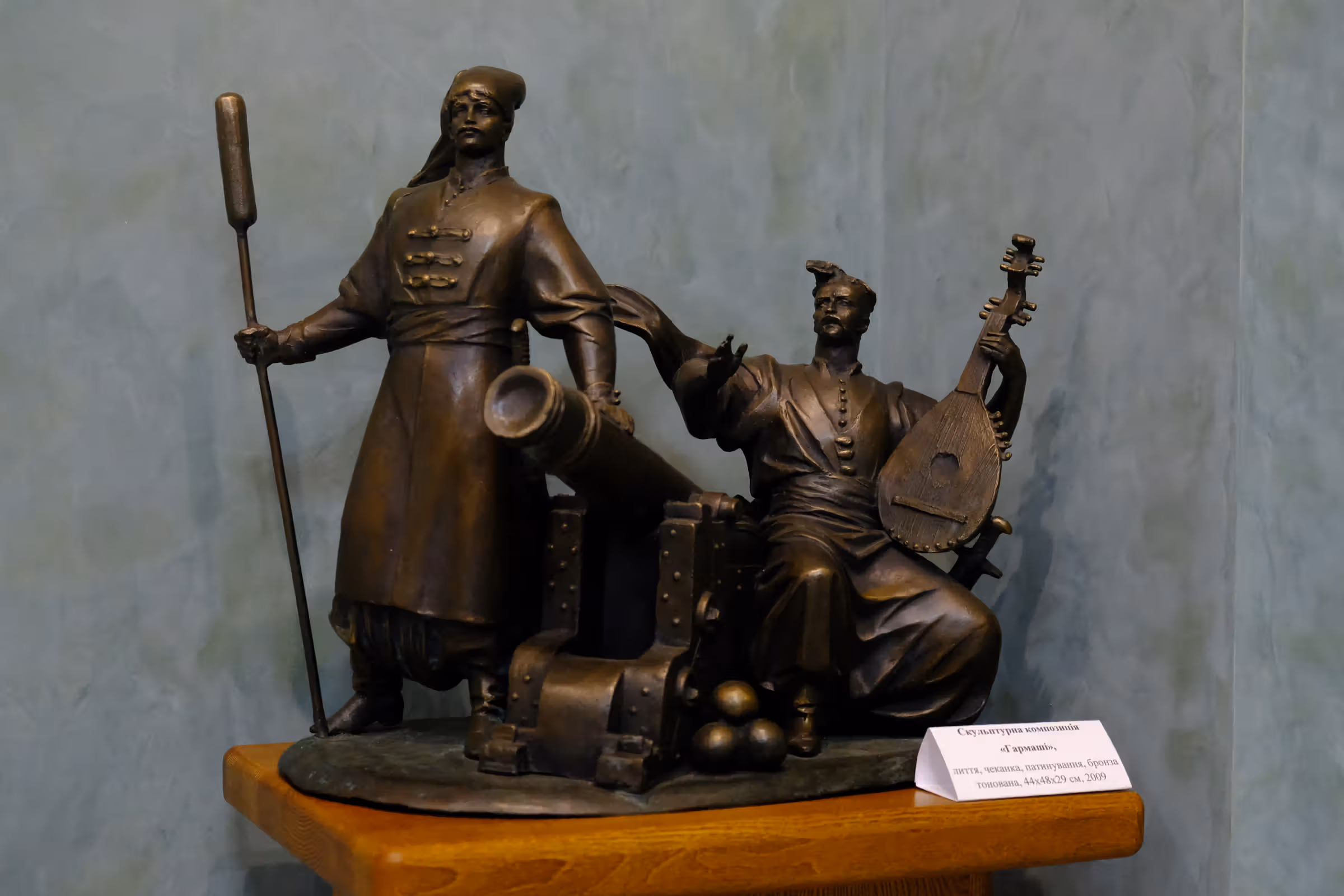 Скульптурна композиція «ГАРМАШІ». Анатолій Васильйович Кущ, 2009 рік. Матеріал скульптурної композиції: бронза тонована. Техніка виконання: лиття, прочеканка, патинування. Розмір скульптурної композиції: 44х48х29 см.